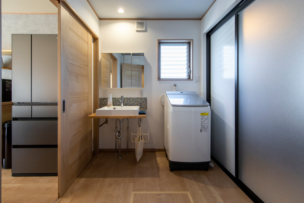 Foto på ett mellanstort beige toalett, med vita skåp, en toalettstol med hel cisternkåpa, flerfärgad kakel, mosaik, vita väggar, plywoodgolv och beiget golv