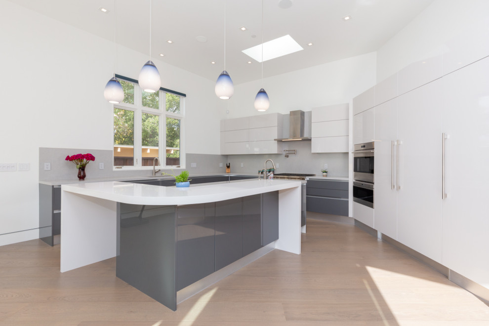 Large contemporary l-shaped open plan kitchen in San Francisco with an undermount sink, flat-panel cabinets, grey cabinets, quartz benchtops, grey splashback, stainless steel appliances, light hardwood floors, with island, brown floor and grey benchtop.