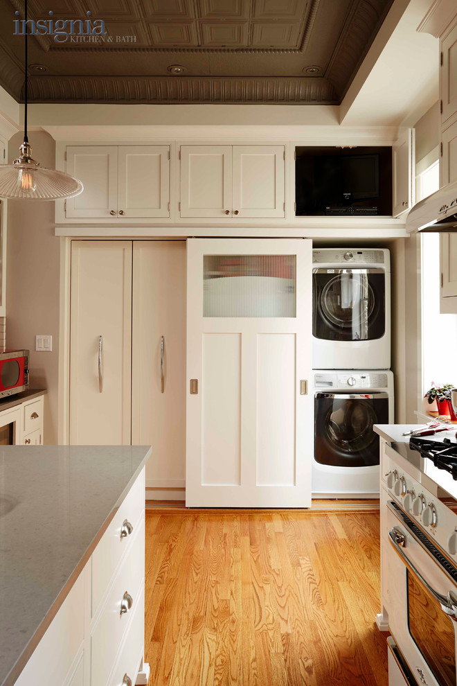 Inspiration for a mid-sized traditional kitchen pantry in Chicago with an undermount sink, beaded inset cabinets, white cabinets, quartz benchtops, white splashback, subway tile splashback, white appliances, light hardwood floors and with island.