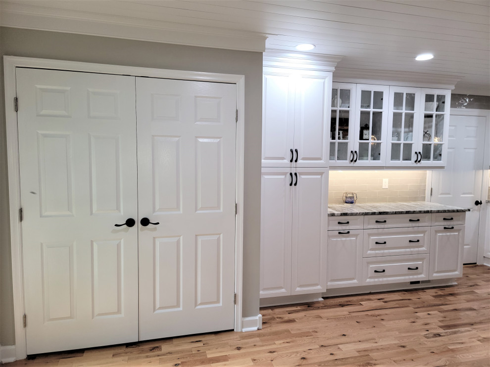 Bild på ett stort rustikt grå grått kök, med en undermonterad diskho, luckor med upphöjd panel, vita skåp, bänkskiva i kvartsit, beige stänkskydd, stänkskydd i porslinskakel, rostfria vitvaror, mellanmörkt trägolv, en köksö och brunt golv