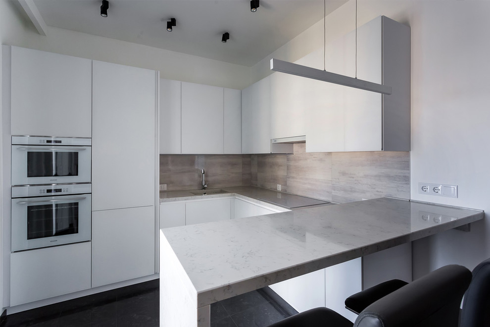 Inspiration for a mid-sized contemporary l-shaped open plan kitchen in Moscow with an integrated sink, flat-panel cabinets, white cabinets, quartz benchtops, grey splashback, porcelain splashback, white appliances, porcelain floors, black floor and white benchtop.