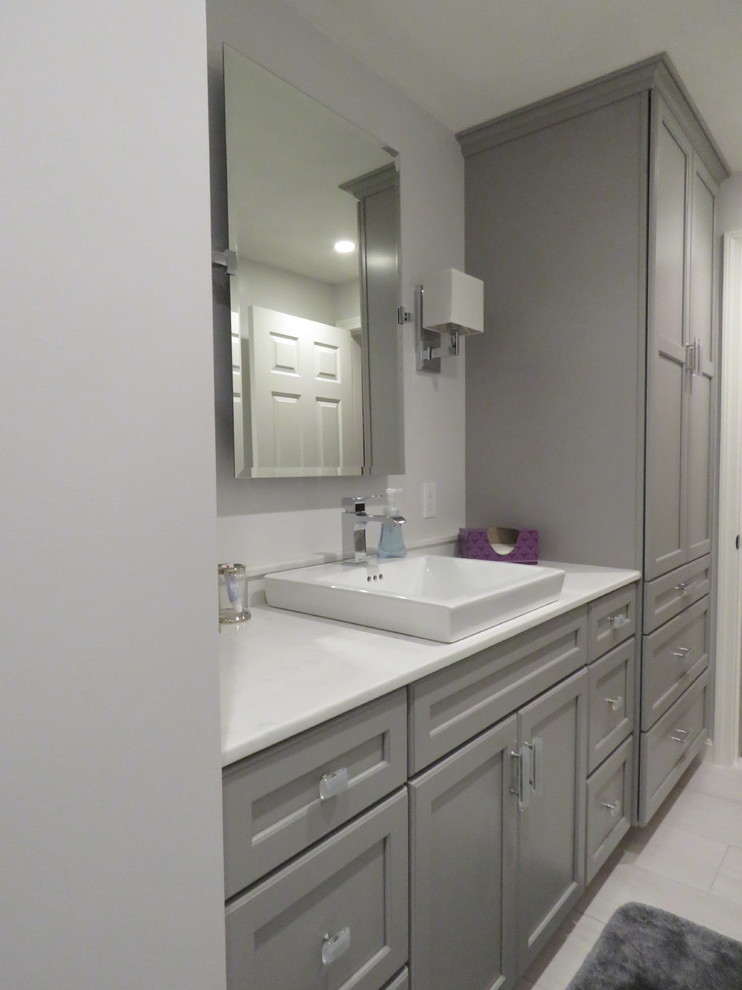 Example of a mid-sized transitional 3/4 porcelain tile alcove shower design in Boston with recessed-panel cabinets, gray cabinets, gray walls, a drop-in sink and marble countertops