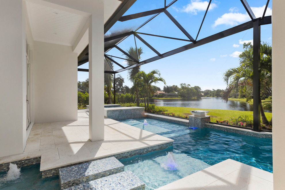 Photo of a large transitional backyard custom-shaped pool in Miami with a hot tub and tile.