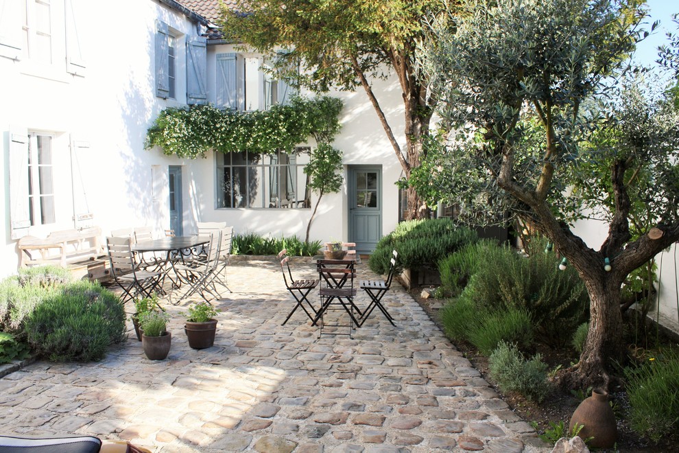 Large country courtyard patio in Rennes with natural stone pavers, a vertical garden and no cover.