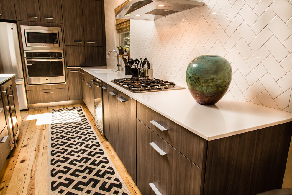 Mid-sized transitional l-shaped medium tone wood floor eat-in kitchen photo with quartz countertops, an undermount sink, flat-panel cabinets, dark wood cabinets, white backsplash, ceramic backsplash, stainless steel appliances and an island