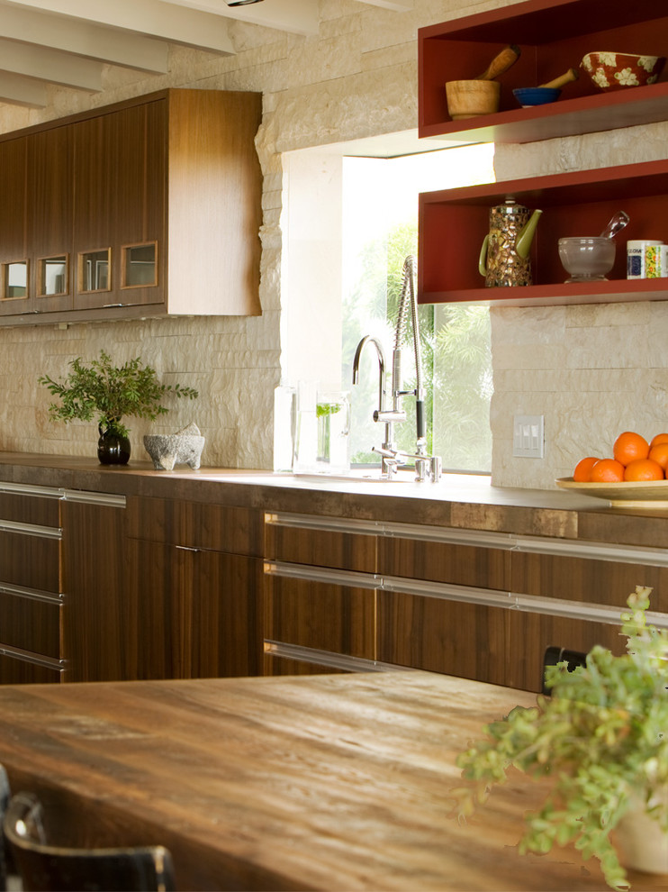 Inspiration for a midcentury kitchen in Orange County with flat-panel cabinets, dark wood cabinets, wood benchtops, beige splashback and limestone splashback.