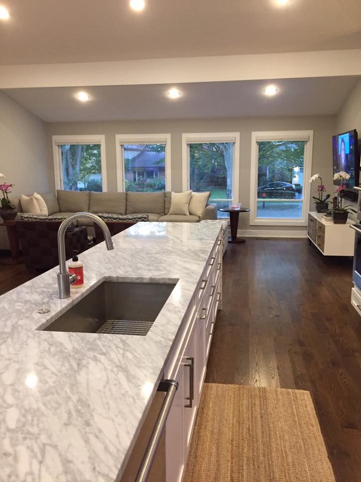 Example of a large transitional u-shaped medium tone wood floor and brown floor open concept kitchen design in Chicago with an undermount sink, shaker cabinets, white cabinets, quartzite countertops, stainless steel appliances and an island