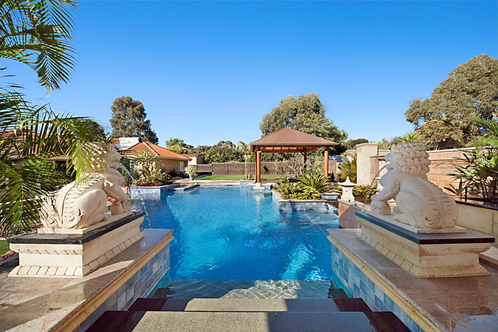 This is an example of an expansive mediterranean backyard custom-shaped infinity pool in Perth with a water feature and decking.