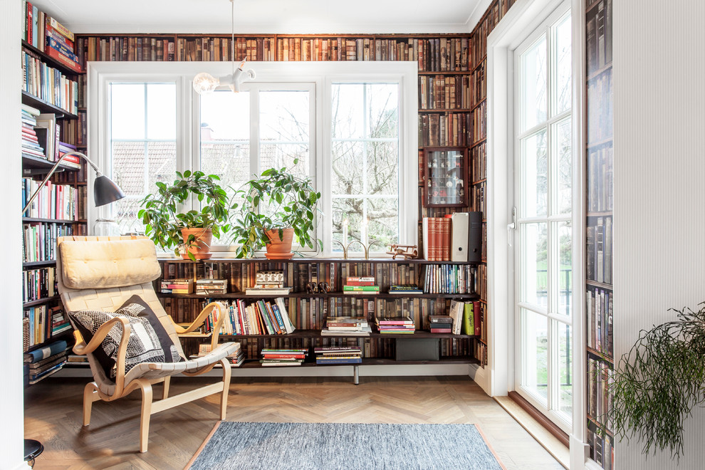 Photo of a small traditional enclosed family room in Gothenburg with a library, multi-coloured walls, light hardwood floors, no tv and brown floor.