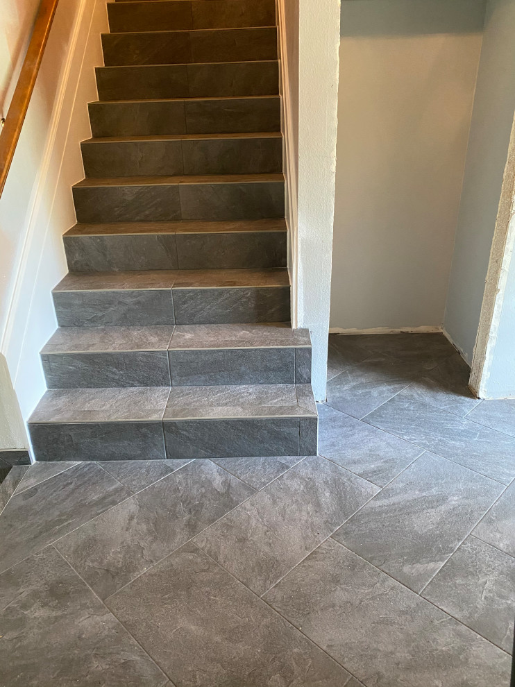 This is an example of a mid-sized tile straight staircase in Portland with tile risers.