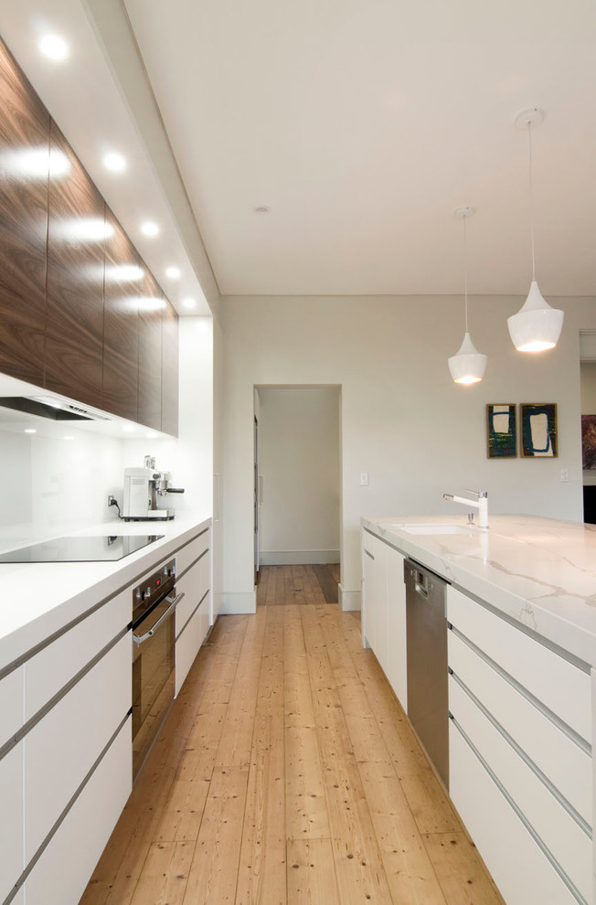 Inspiration for a large modern single-wall open plan kitchen in Sydney with an undermount sink, flat-panel cabinets, quartz benchtops, white splashback, glass sheet splashback, stainless steel appliances, light hardwood floors, with island and medium wood cabinets.