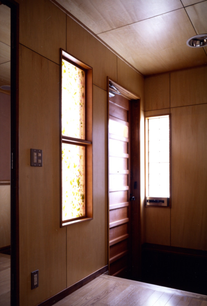 Идея дизайна: входная дверь среднего размера со шкафом для обуви в стиле модернизм с коричневыми стенами, светлым паркетным полом, одностворчатой входной дверью, входной дверью из темного дерева, коричневым полом, потолком из вагонки и стенами из вагонки