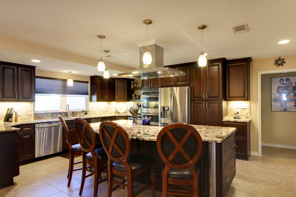 Large transitional l-shaped porcelain tile eat-in kitchen photo in Miami with an undermount sink, raised-panel cabinets, dark wood cabinets, granite countertops, beige backsplash, stone tile backsplash, stainless steel appliances and an island