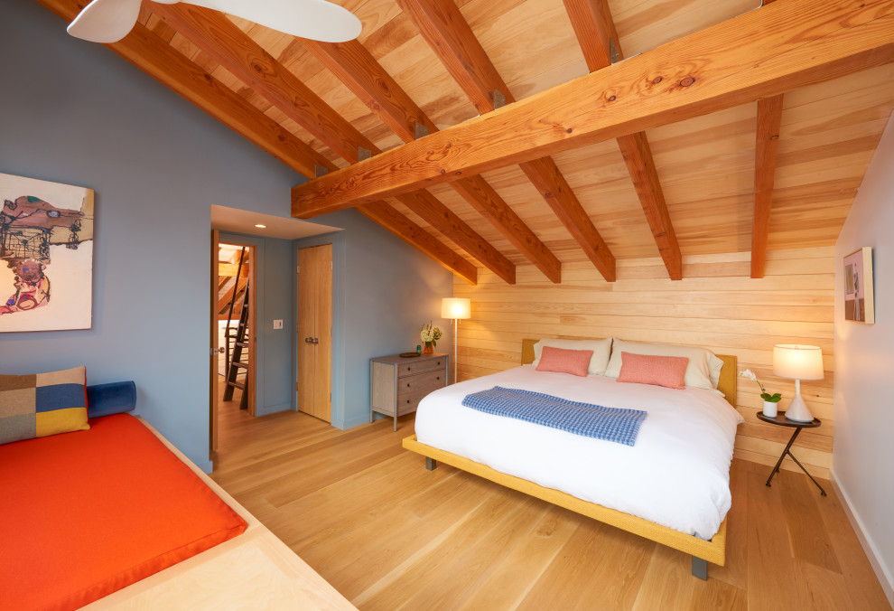 Großes Rustikales Gästezimmer mit blauer Wandfarbe, braunem Holzboden, freigelegten Dachbalken und Holzwänden