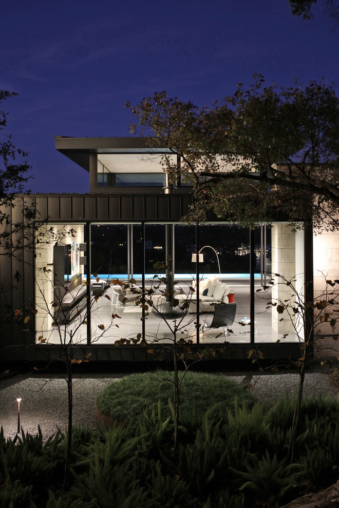 Photo of a large contemporary two-storey black house exterior in Austin with metal siding, a flat roof and a metal roof.