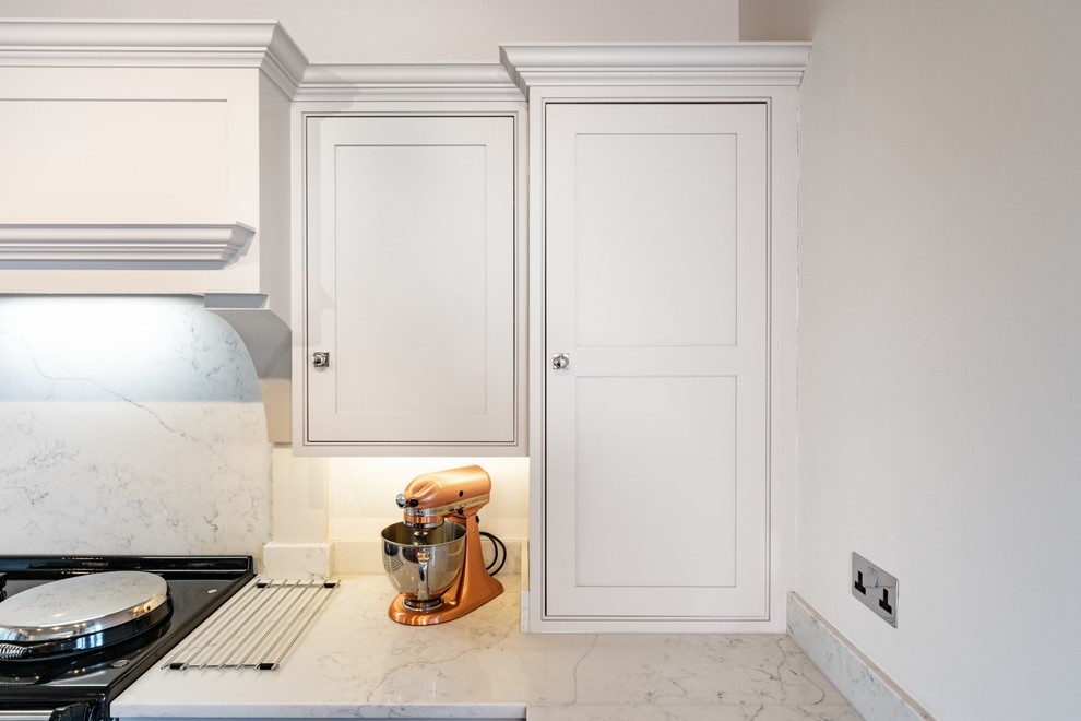 Photo of a small transitional u-shaped eat-in kitchen in Essex with recessed-panel cabinets, white cabinets, quartzite benchtops, white splashback, marble splashback and white benchtop.