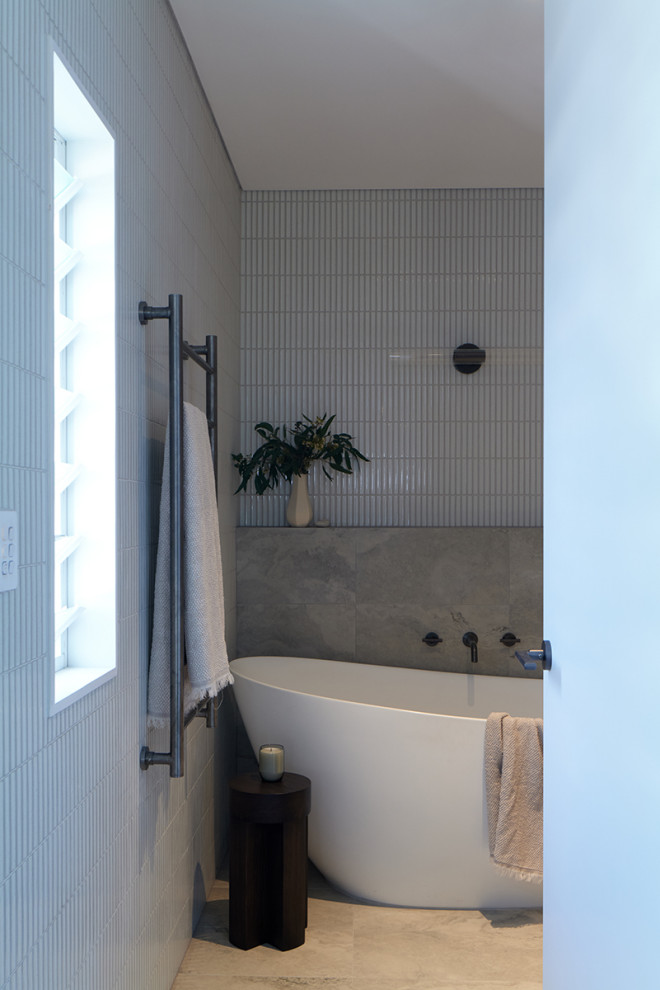 На фото: главная ванная комната среднего размера в современном стиле с фасадами в стиле шейкер, белыми фасадами, отдельно стоящей ванной, открытым душем, унитазом-моноблоком, белой плиткой, плиткой из травертина, белыми стенами, полом из травертина, врезной раковиной, мраморной столешницей, разноцветным полом, открытым душем, белой столешницей, нишей, тумбой под две раковины, встроенной тумбой и панелями на стенах с