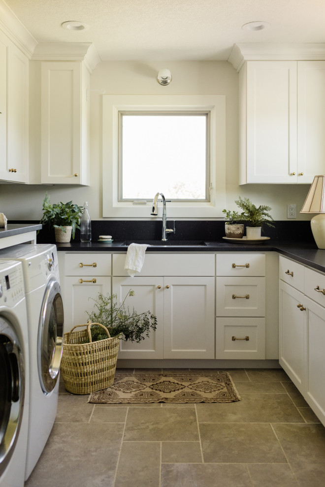 Idéer för en mellanstor klassisk svarta u-formad tvättstuga enbart för tvätt, med en undermonterad diskho, luckor med infälld panel, vita skåp, bänkskiva i kvarts, svart stänkskydd, vita väggar, klinkergolv i keramik, en tvättmaskin och torktumlare bredvid varandra och grått golv