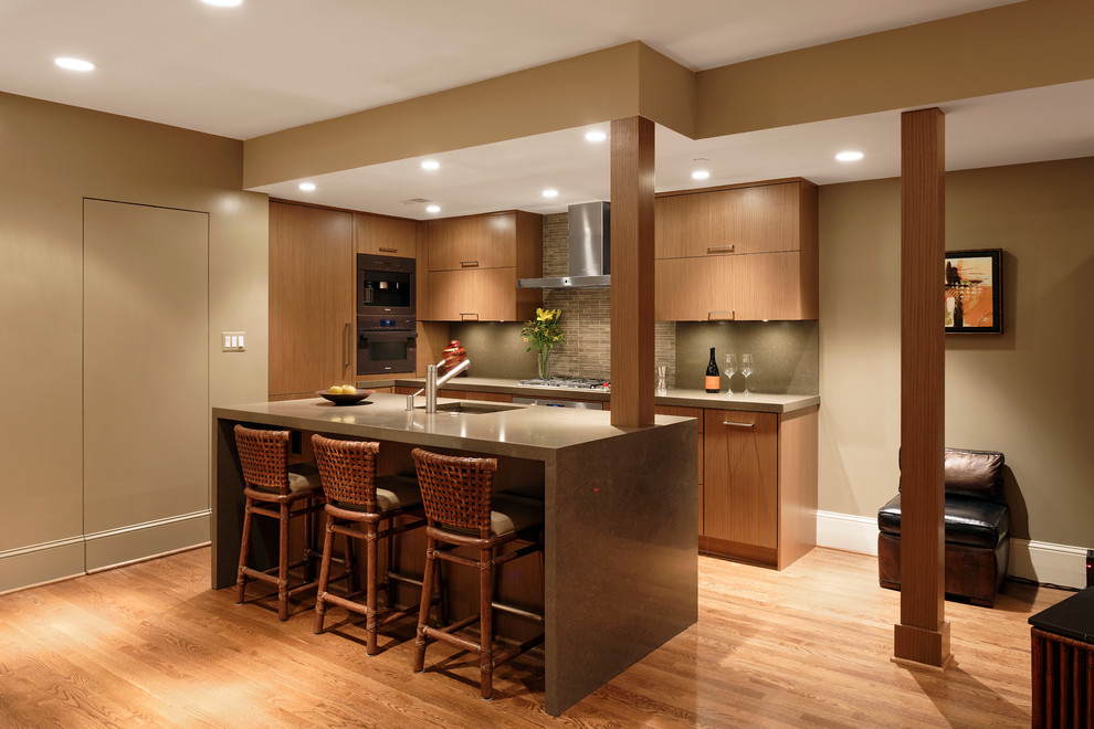 Mid-sized contemporary u-shaped eat-in kitchen in DC Metro with flat-panel cabinets, medium wood cabinets, quartz benchtops, grey splashback, stone tile splashback, panelled appliances, medium hardwood floors and with island.