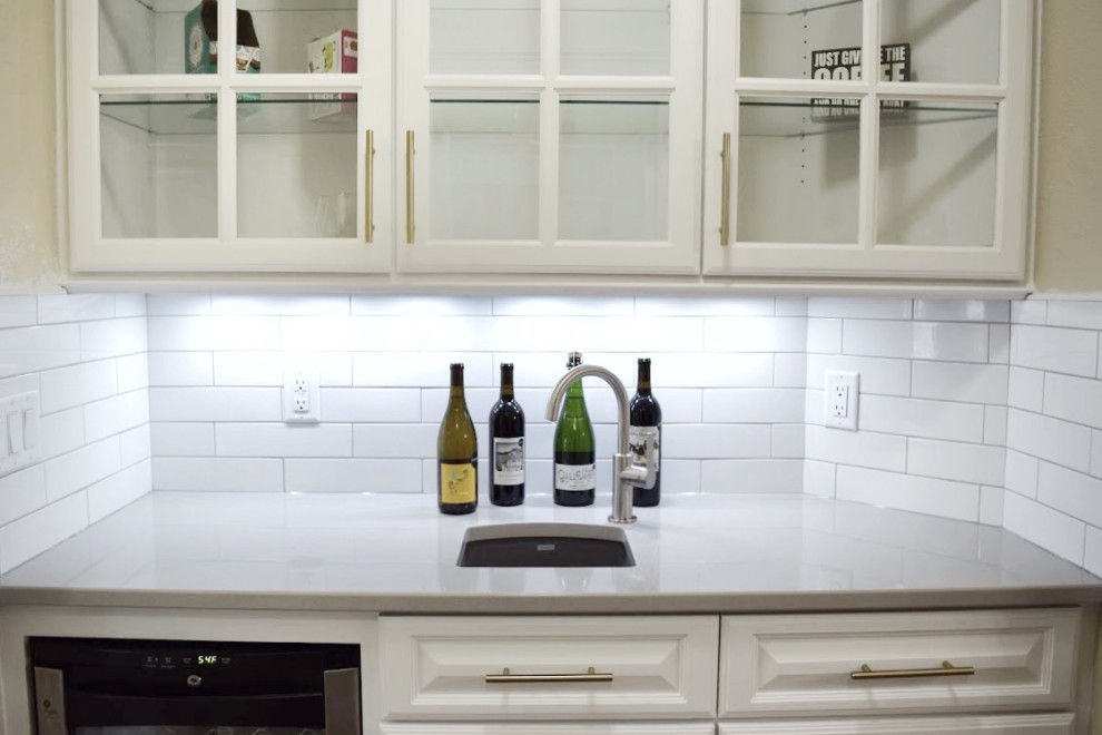 Kitchen pantry - transitional dark wood floor kitchen pantry idea in Milwaukee with an undermount sink, glass-front cabinets, white cabinets, white backsplash, stainless steel appliances and gray countertops