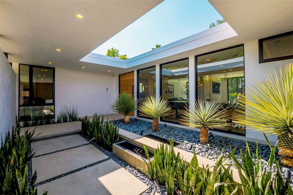 Mid-sized modern courtyard patio in Los Angeles with a water feature, concrete pavers and no cover.