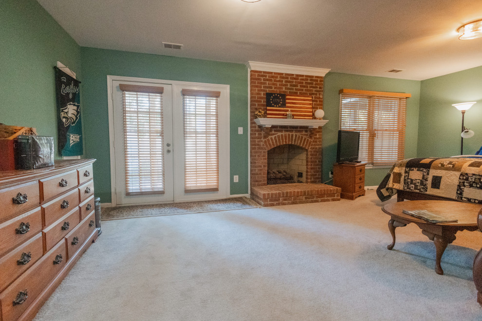 Example of a large classic walk-out carpeted and gray floor basement design in DC Metro with green walls, a standard fireplace and a brick fireplace