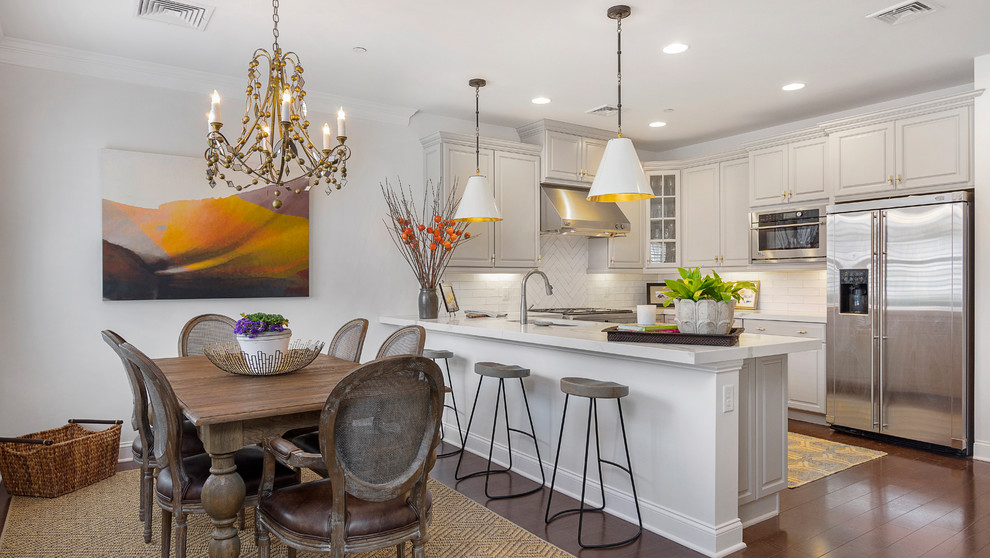 Example of a mid-sized transitional u-shaped medium tone wood floor and brown floor eat-in kitchen design in Boston with an undermount sink, raised-panel cabinets, white cabinets, quartz countertops, white backsplash, stainless steel appliances, a peninsula and white countertops