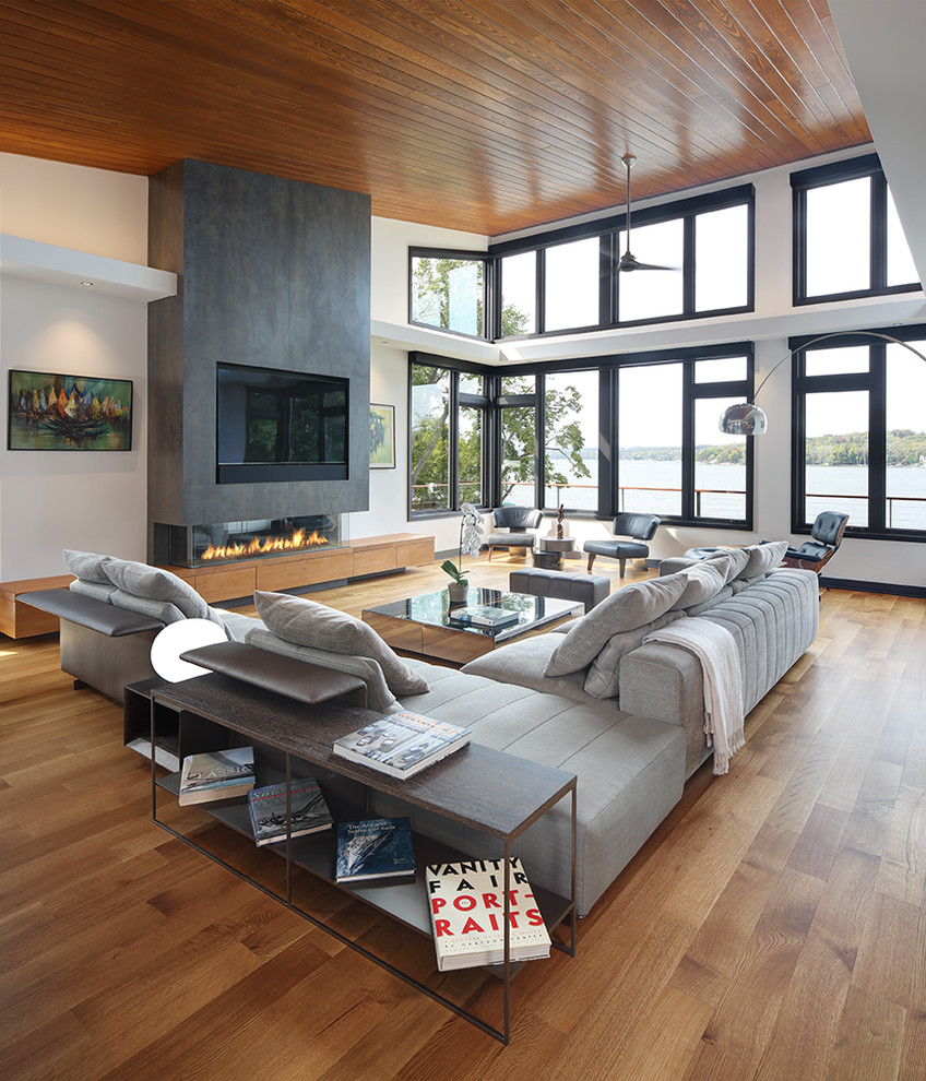 Example of a trendy open concept medium tone wood floor family room design in Milwaukee with white walls, a ribbon fireplace and a wall-mounted tv