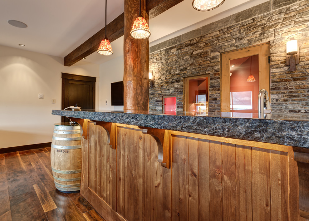 Country home bar in Vancouver with an undermount sink, beaded inset cabinets, medium wood cabinets, solid surface benchtops, multi-coloured splashback, stone tile splashback and medium hardwood floors.
