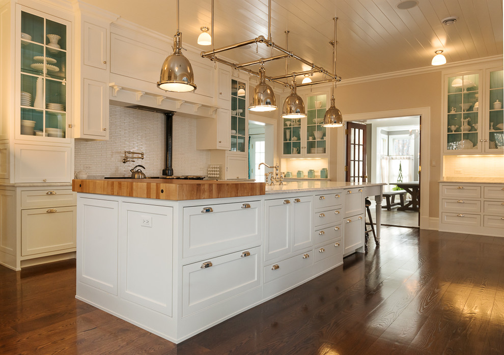 This is an example of a large traditional u-shaped eat-in kitchen in Chicago with flat-panel cabinets, white cabinets, wood benchtops, white splashback, stone tile splashback, medium hardwood floors and with island.