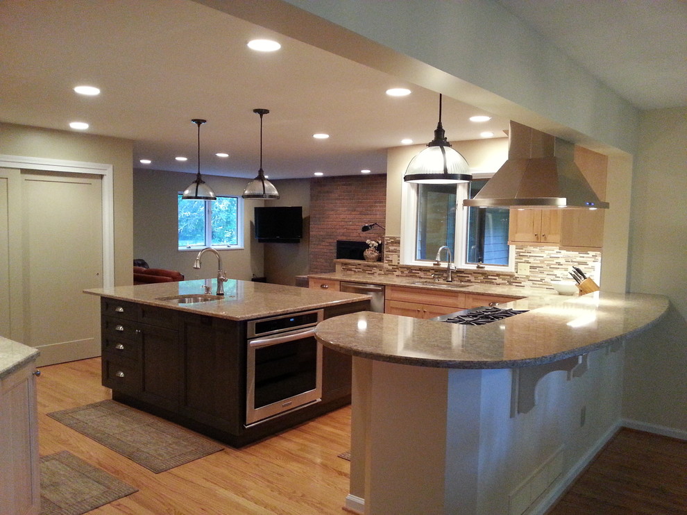 Mid-sized transitional l-shaped medium tone wood floor kitchen pantry photo in New York with an undermount sink, raised-panel cabinets, light wood cabinets, glass countertops, beige backsplash, stone slab backsplash, stainless steel appliances and an island