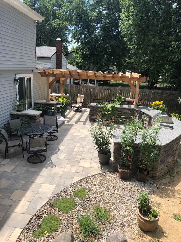Design ideas for an expansive eclectic backyard patio in Columbus with an outdoor kitchen, brick pavers and a pergola.