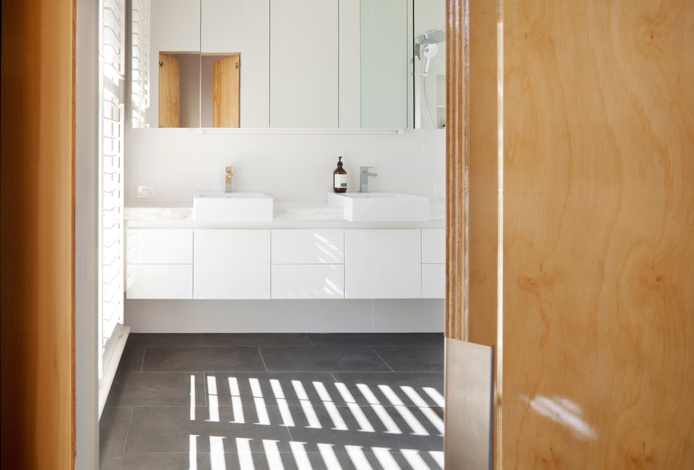This is an example of a small contemporary 3/4 bathroom in Melbourne with a vessel sink, flat-panel cabinets, white cabinets, marble benchtops, an open shower, a wall-mount toilet, white tile, porcelain tile, white walls and limestone floors.