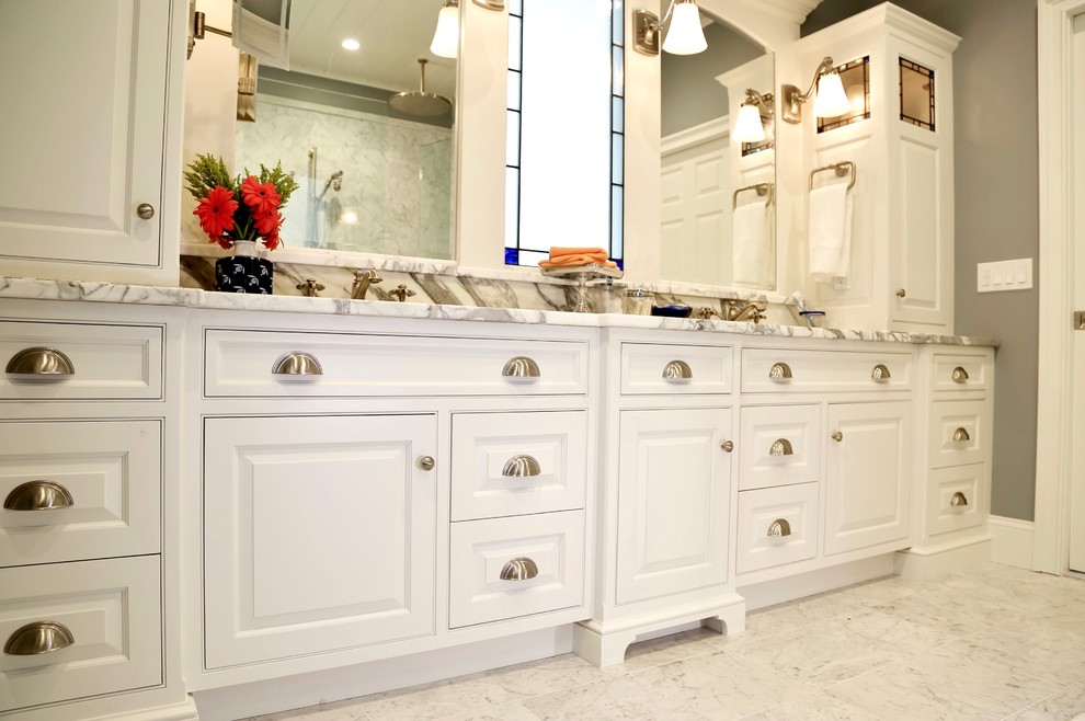 Example of a mid-sized transitional master white tile and marble tile marble floor and white floor corner shower design with raised-panel cabinets, white cabinets, a one-piece toilet, gray walls, an undermount sink and marble countertops