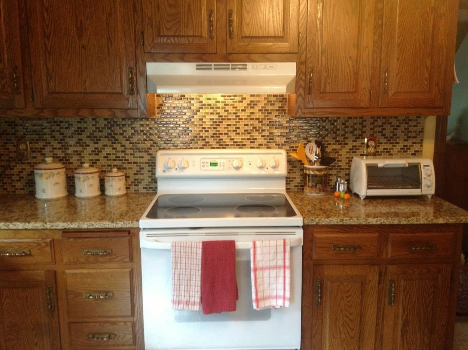 Mid-sized single-wall open concept kitchen photo with raised-panel cabinets, medium tone wood cabinets, granite countertops, multicolored backsplash, glass tile backsplash and white appliances