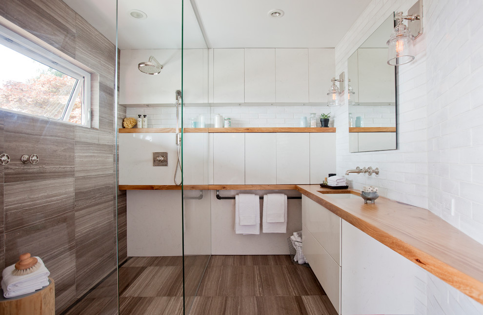 Photo of a mid-sized transitional 3/4 bathroom in Vancouver with flat-panel cabinets, white cabinets, an open shower, a two-piece toilet, white tile, beige tile, stone slab, white walls, an undermount sink, wood benchtops and an open shower.