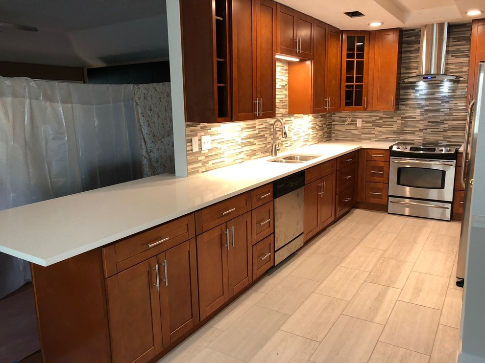Design ideas for a mid-sized transitional u-shaped separate kitchen in Houston with an undermount sink, shaker cabinets, medium wood cabinets, quartz benchtops, multi-coloured splashback, glass tile splashback, stainless steel appliances, porcelain floors, no island, grey floor and white benchtop.