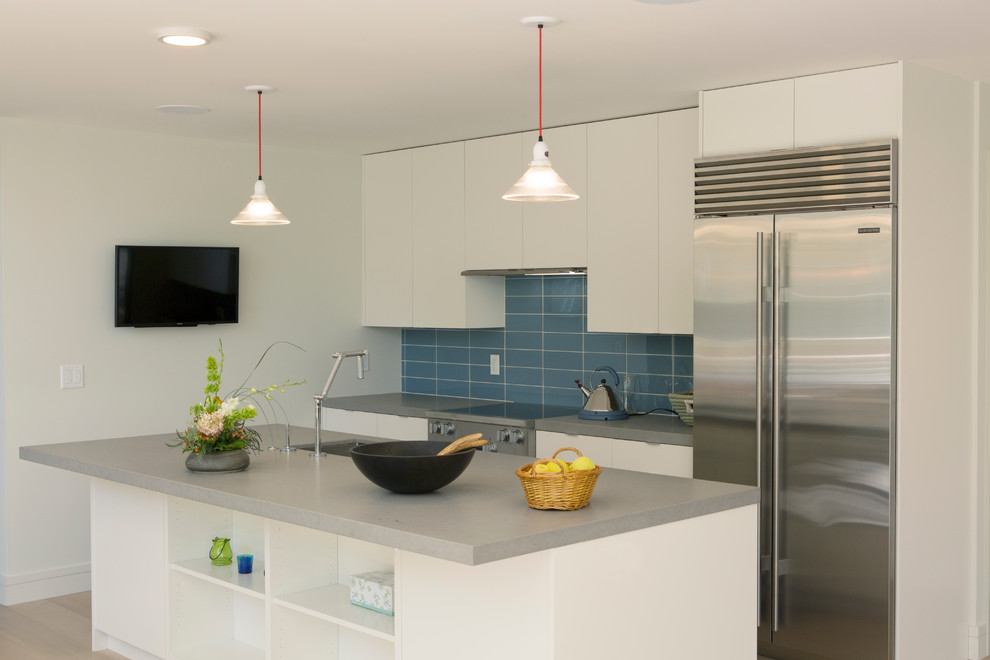 Inspiration for a mid-sized modern single-wall light wood floor eat-in kitchen remodel in Boston with an undermount sink, flat-panel cabinets, white cabinets, solid surface countertops, blue backsplash, glass tile backsplash, stainless steel appliances and an island