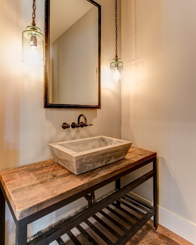 Design ideas for an industrial powder room in Other with furniture-like cabinets, beige walls, medium hardwood floors, a vessel sink, wood benchtops and brown benchtops.