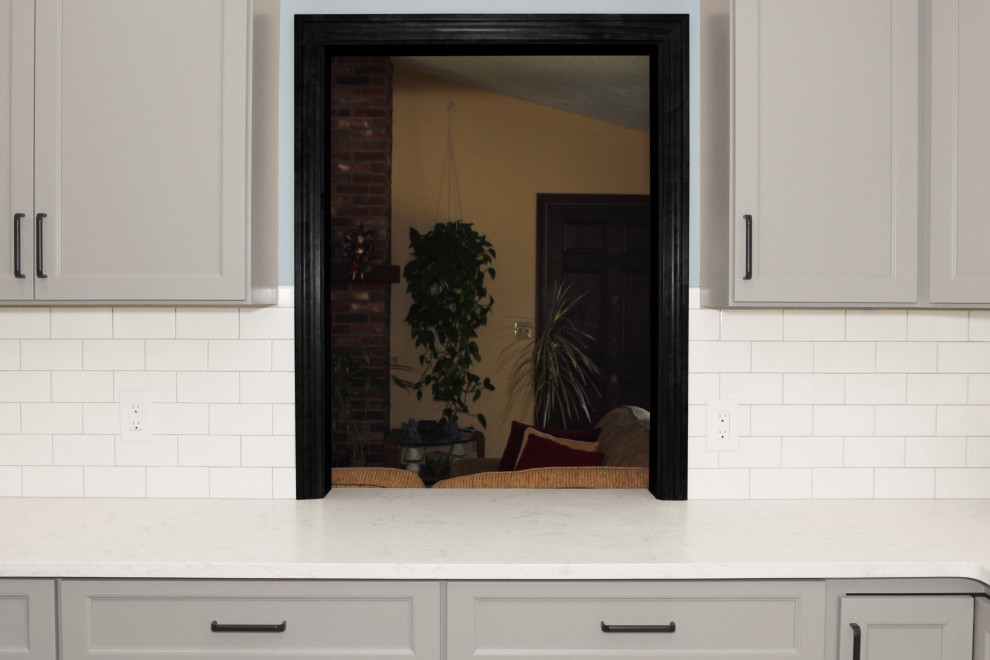 Large transitional u-shaped light wood floor and brown floor enclosed kitchen photo in Boston with a double-bowl sink, shaker cabinets, gray cabinets, quartz countertops, white backsplash, porcelain backsplash, black appliances, an island and white countertops