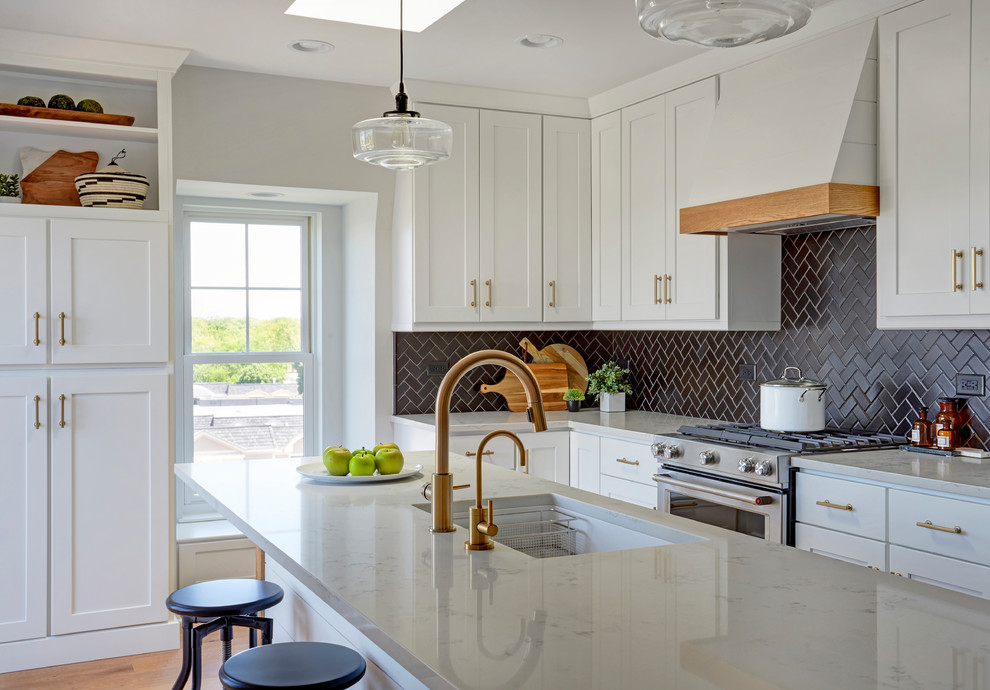 Mid-sized beach style l-shaped medium tone wood floor and brown floor eat-in kitchen photo in Chicago with an undermount sink, shaker cabinets, white cabinets, quartz countertops, black backsplash, ceramic backsplash, stainless steel appliances, an island and white countertops