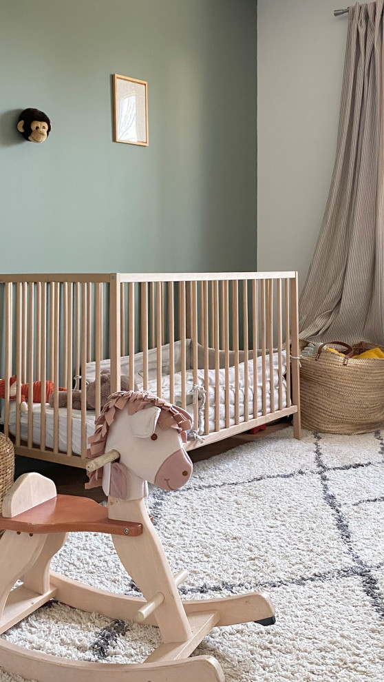 This is an example of a mid-sized contemporary nursery for boys in Marseille with green walls, light hardwood floors and beige floor.