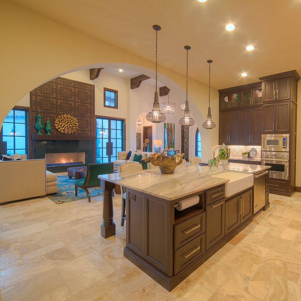 This is an example of a large mediterranean u-shaped open plan kitchen in Austin with an undermount sink, recessed-panel cabinets, dark wood cabinets, granite benchtops, multi-coloured splashback, mosaic tile splashback, stainless steel appliances, ceramic floors and beige floor.
