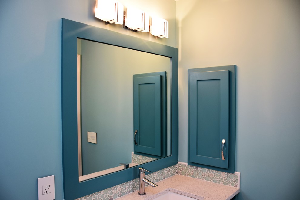 Inspiration for a mid-sized arts and crafts kids bathroom in Kansas City with flat-panel cabinets, blue cabinets, an alcove tub, a shower/bathtub combo, a two-piece toilet, multi-coloured tile, glass tile, blue walls, ceramic floors, an undermount sink and engineered quartz benchtops.