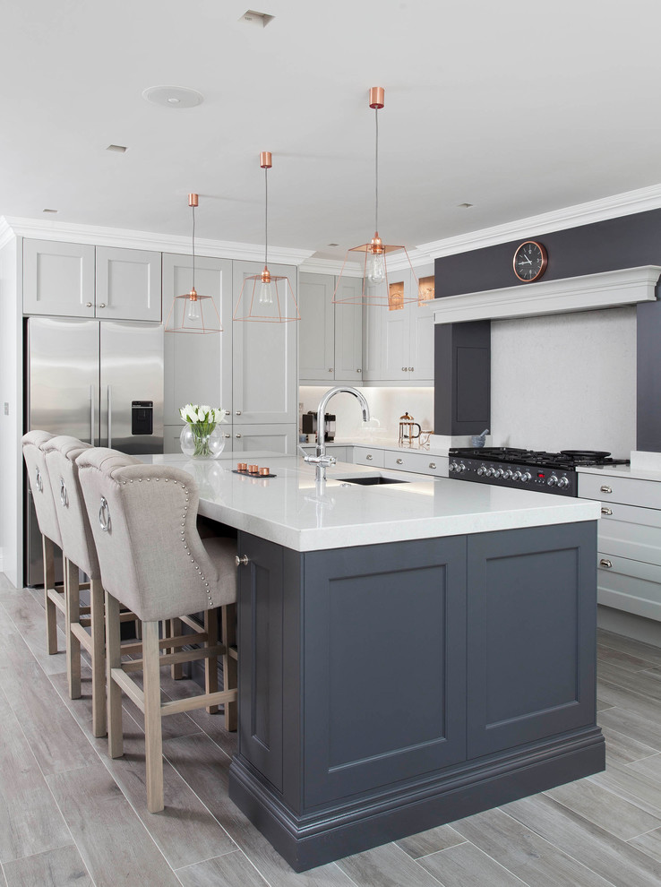 This is an example of a large traditional l-shaped open plan kitchen in Other with an undermount sink, shaker cabinets, grey cabinets, quartzite benchtops, grey splashback, stone slab splashback, stainless steel appliances, porcelain floors, with island and brown floor.