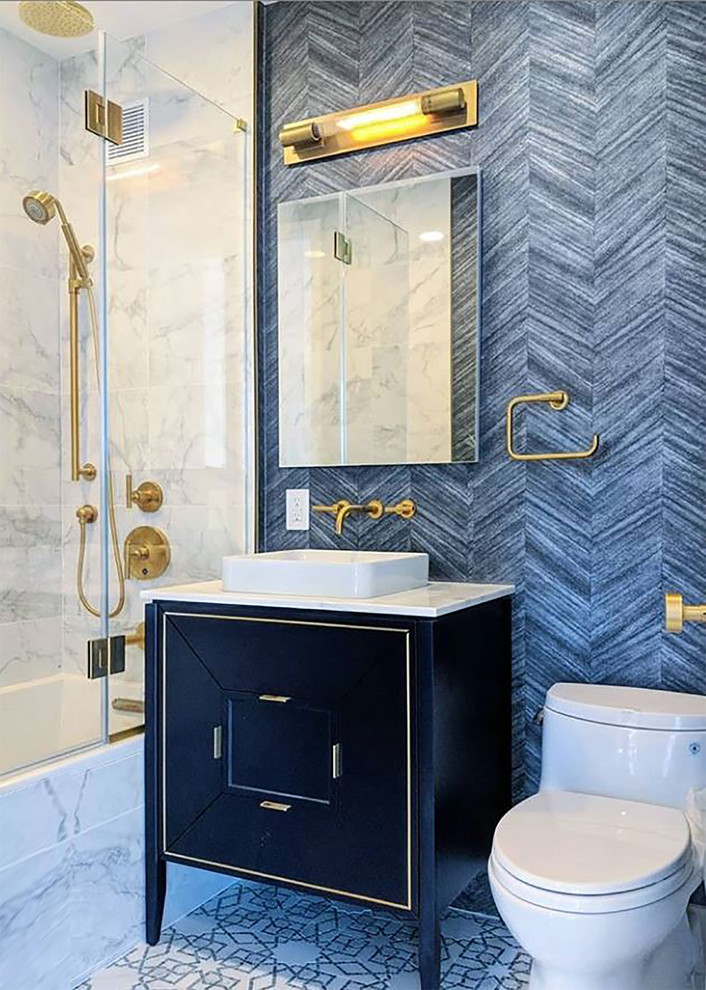 This is an example of a small contemporary kids bathroom in New York with flat-panel cabinets, blue cabinets, a drop-in tub, a shower/bathtub combo, a two-piece toilet, white tile, porcelain tile, blue walls, marble floors, a vessel sink, marble benchtops, yellow floor, a hinged shower door and white benchtops.