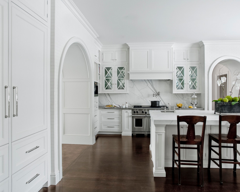 Photo of a traditional single-wall kitchen in Detroit with beaded inset cabinets, white cabinets, marble benchtops, white splashback, stone slab splashback, with island, an undermount sink, stainless steel appliances and dark hardwood floors.