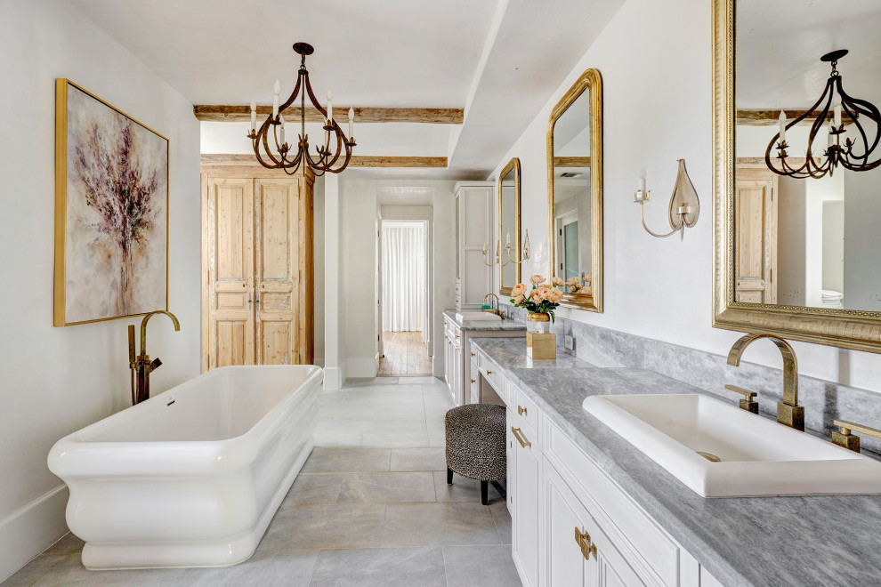 Farmhouse master limestone floor, gray floor, double-sink and exposed beam bathroom photo in Houston with recessed-panel cabinets, gray cabinets, white walls, a drop-in sink, marble countertops, gray countertops and a built-in vanity
