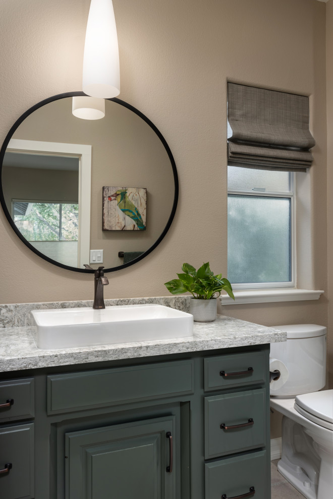 Photo of a mid-sized bathroom in Other with raised-panel cabinets, green cabinets, a corner tub, a shower/bathtub combo, a two-piece toilet, beige walls, porcelain floors, a vessel sink, engineered quartz benchtops, beige floor, a sliding shower screen, grey benchtops, a single vanity and a built-in vanity.