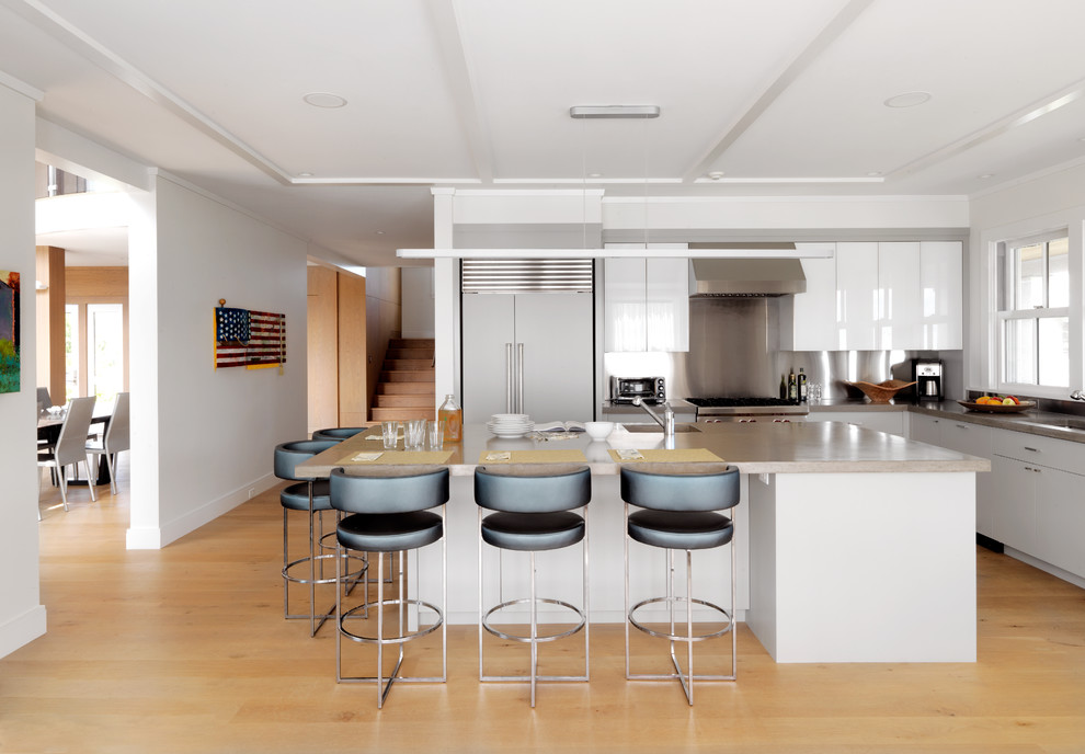 This is an example of a contemporary l-shaped kitchen in Boston with concrete benchtops, flat-panel cabinets, metallic splashback, metal splashback and stainless steel appliances.